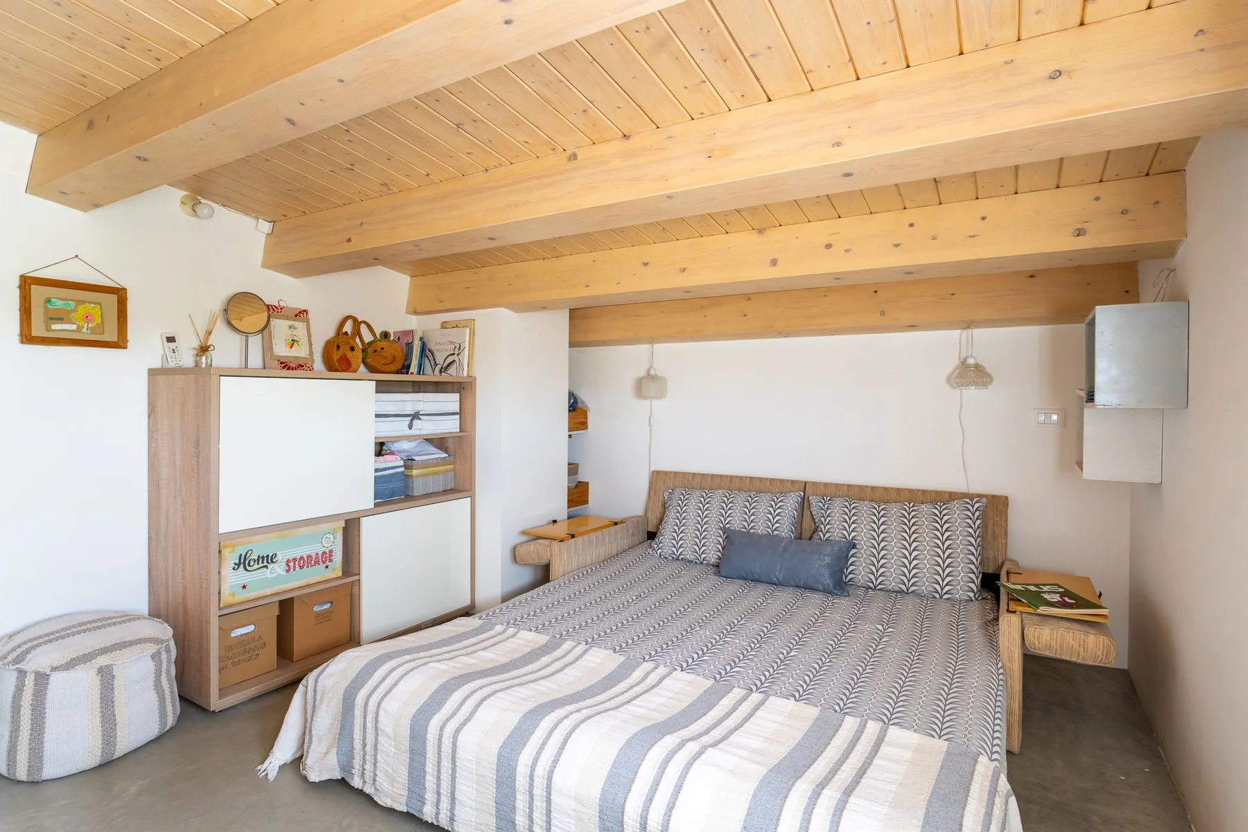 Un dormitorio con una cama grande bajo vigas de madera vistas.