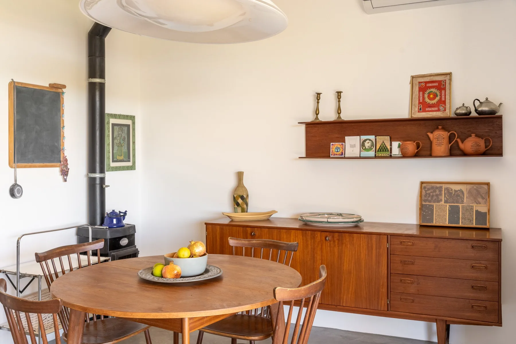 Un comedor con una mesa redonda de madera y un aparador junto a la pared.