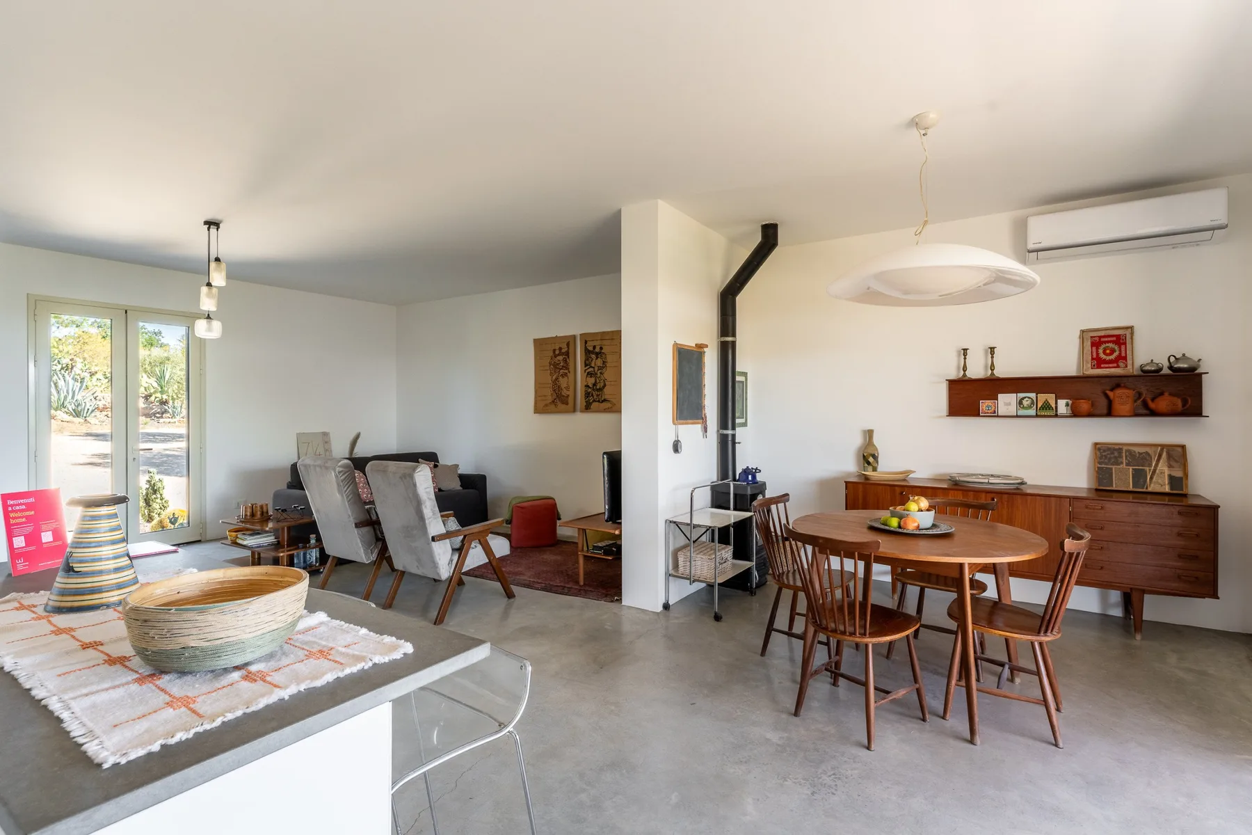 Una luminosa sala de estar y comedor diáfana, con asientos y una mesa de madera.