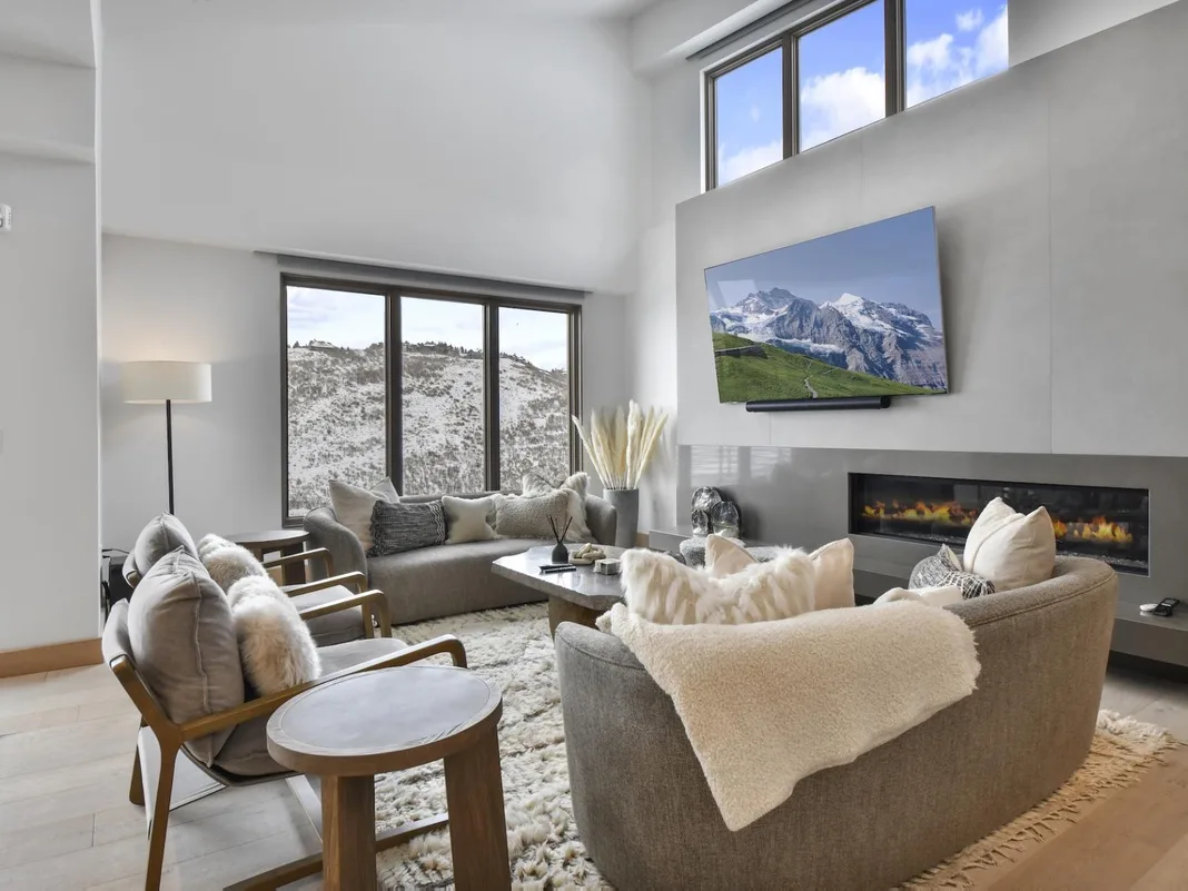 A bright living room with seating, a fireplace, and large windows.