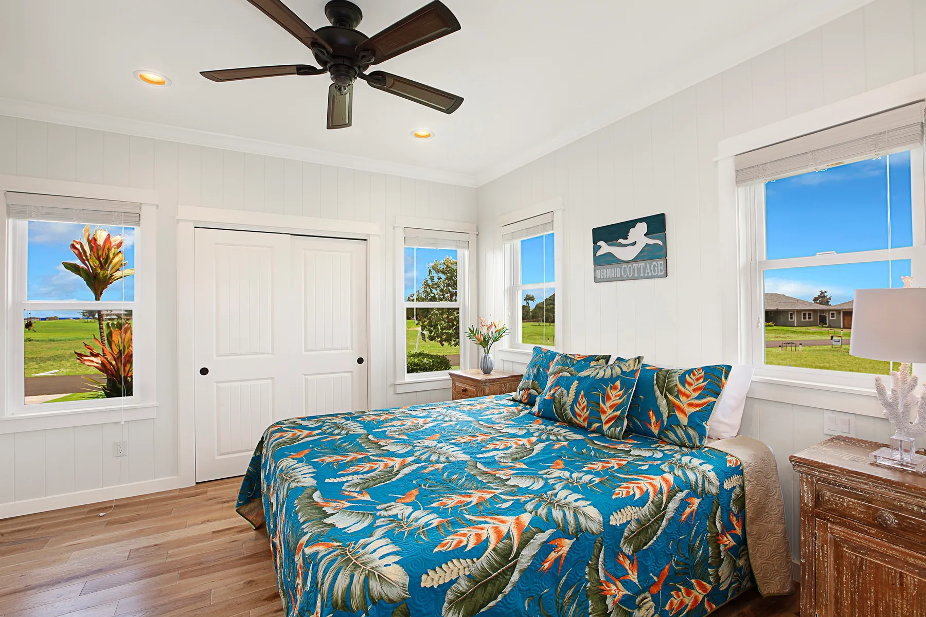Un dormitorio luminoso con una cama cubierta con una colcha de estampado tropical.