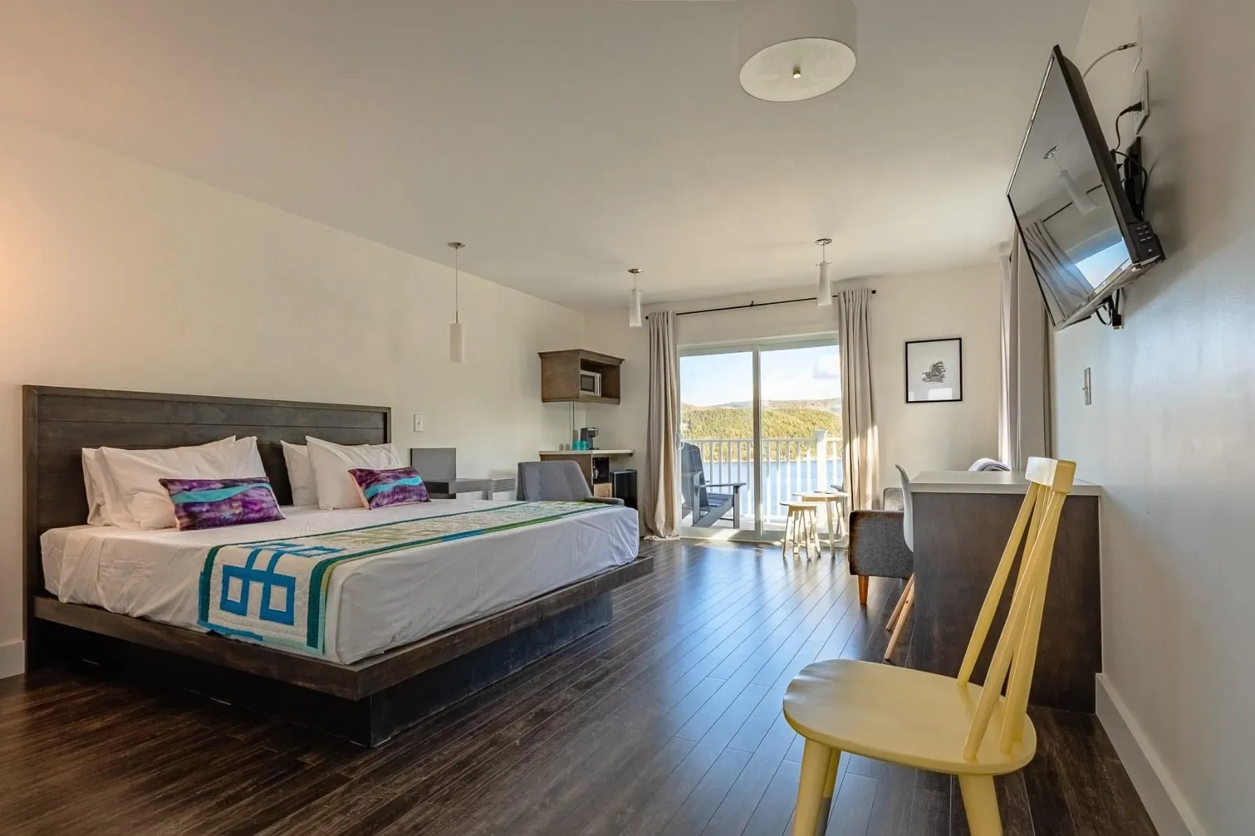 Hotel room with a king bed, yellow chair, and flat-screen TV
