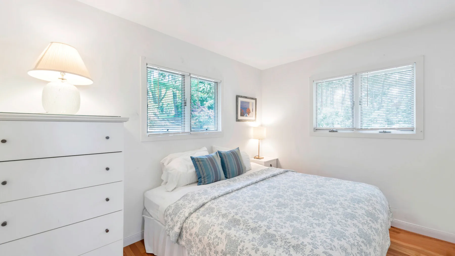 Un dormitorio luminoso con una cama y dos ventanas.