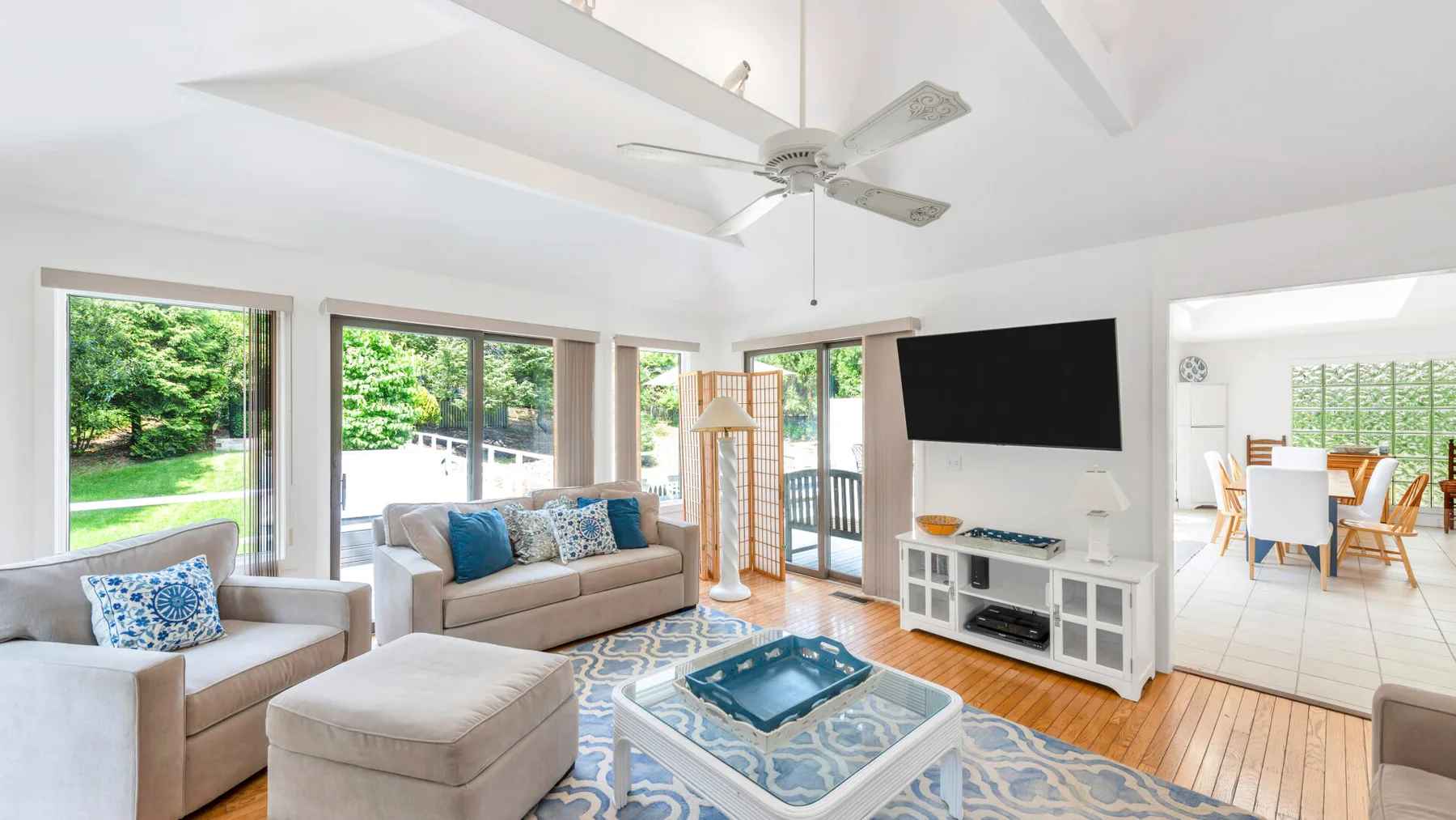A bright living room with seating, large windows, and a television.