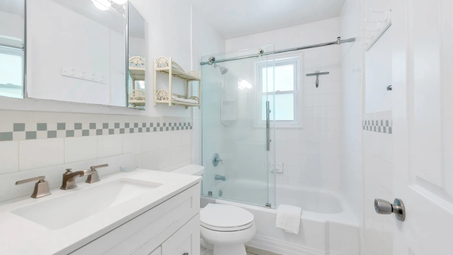 Un baño luminoso con una ducha de vidrio y un lavabo blanco.
