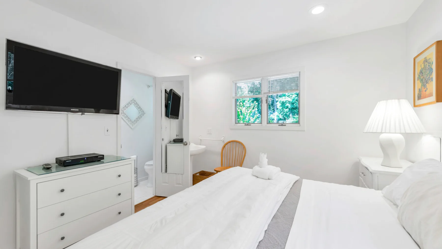 Un dormitorio luminoso con dos camas, un televisor y una ventana.