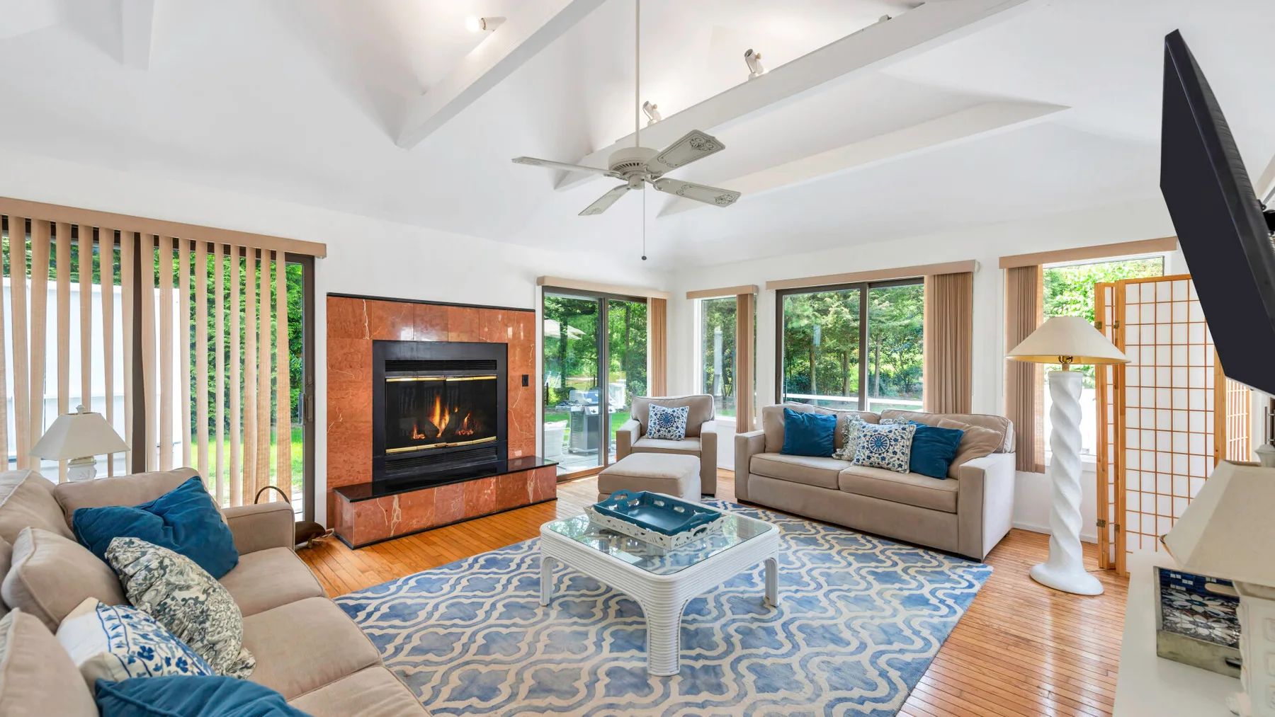 A bright living room with seating around a glass coffee table and patterned rug.