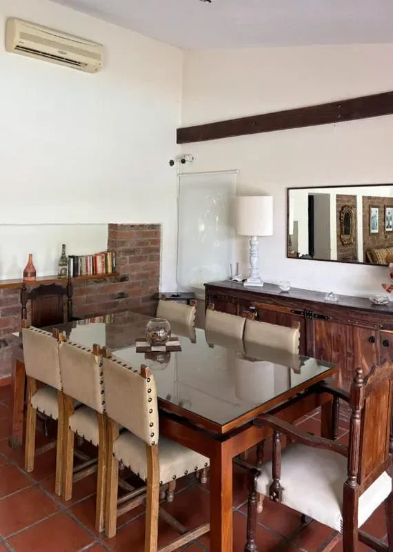 A dining room with a glass-topped table and wooden seating.