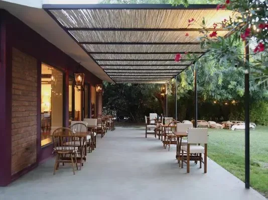 A covered outdoor patio with seating beside a garden.