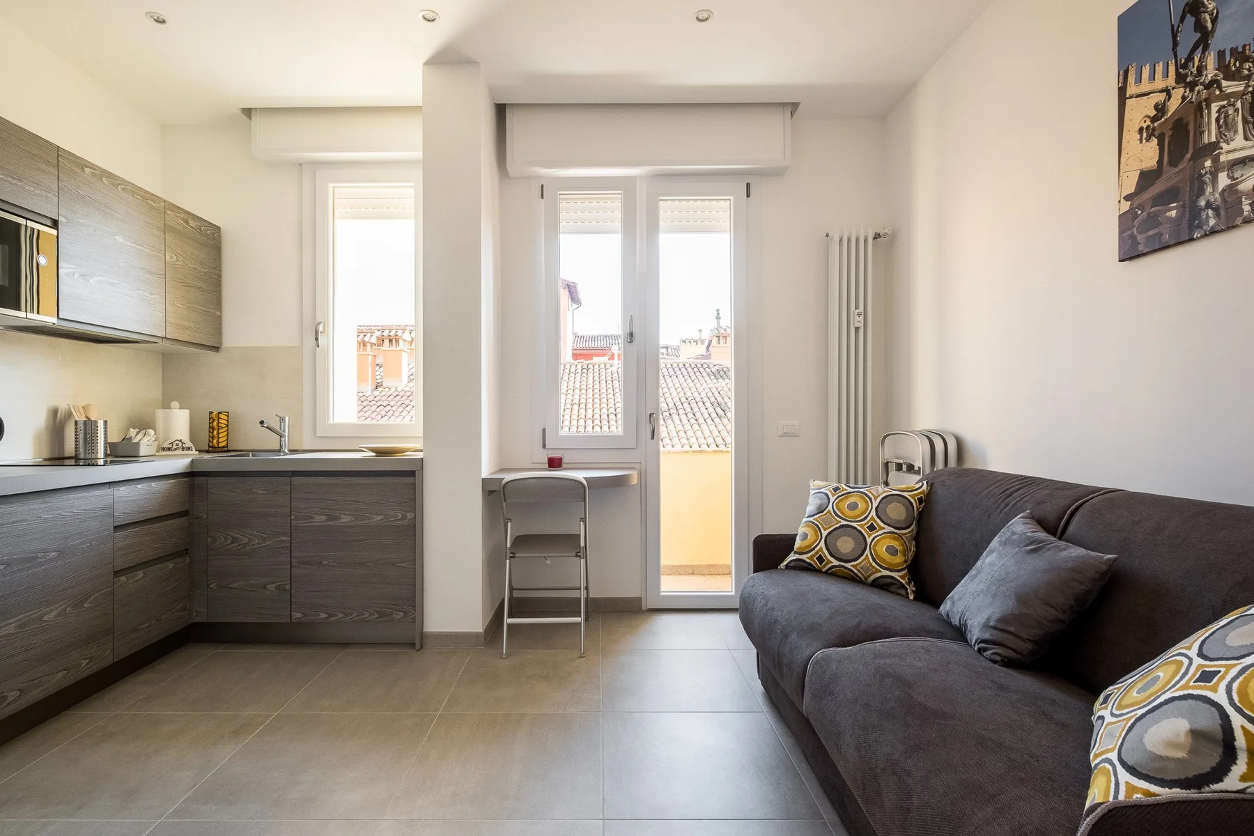 A compact living area with a dark sofa beside a modern kitchen.