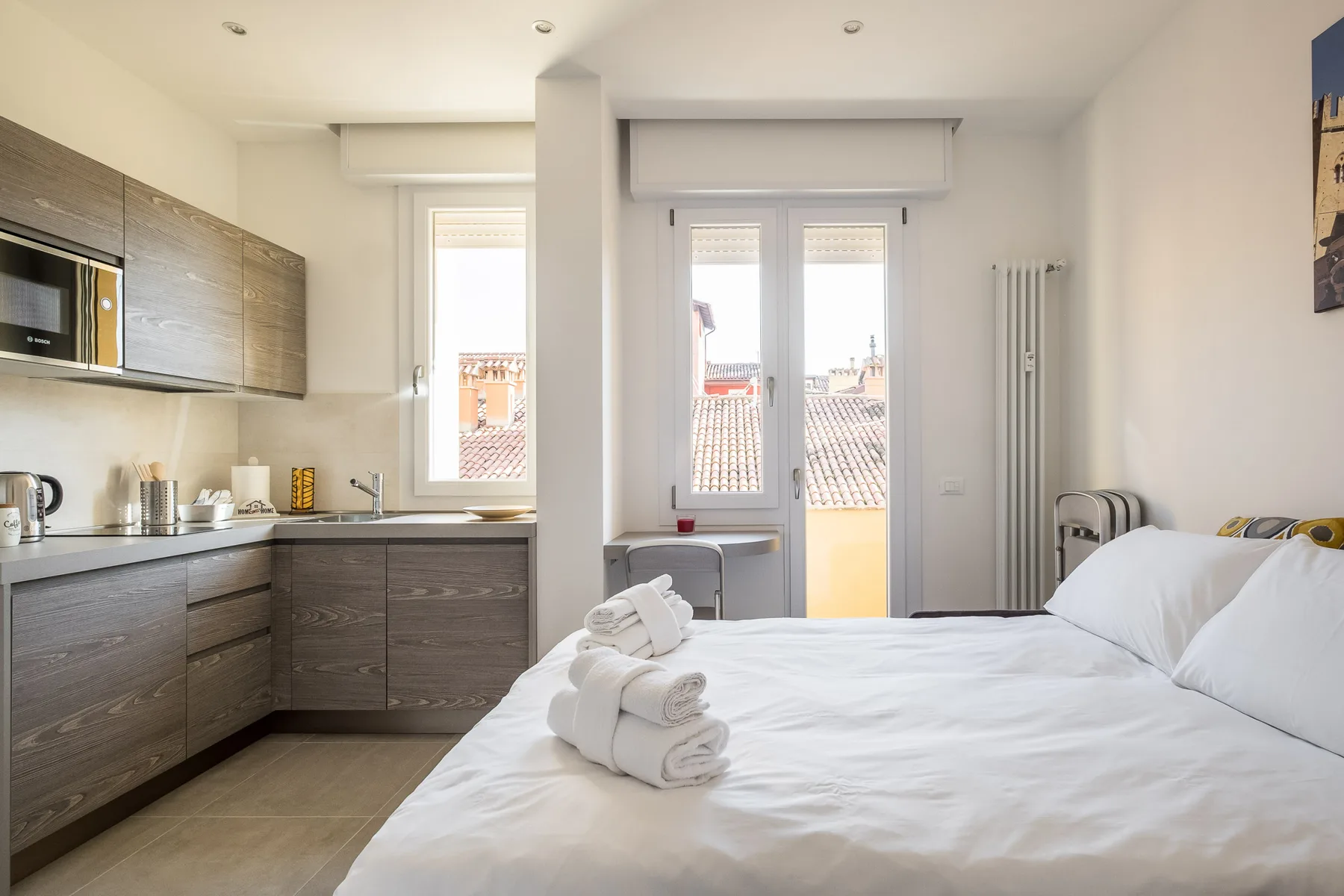 A bedroom with a bed and a compact kitchen along one wall.