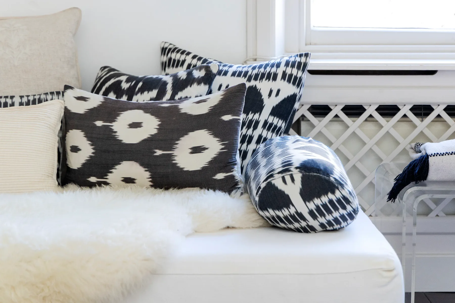 A cushioned seating area with patterned pillows and a white throw.