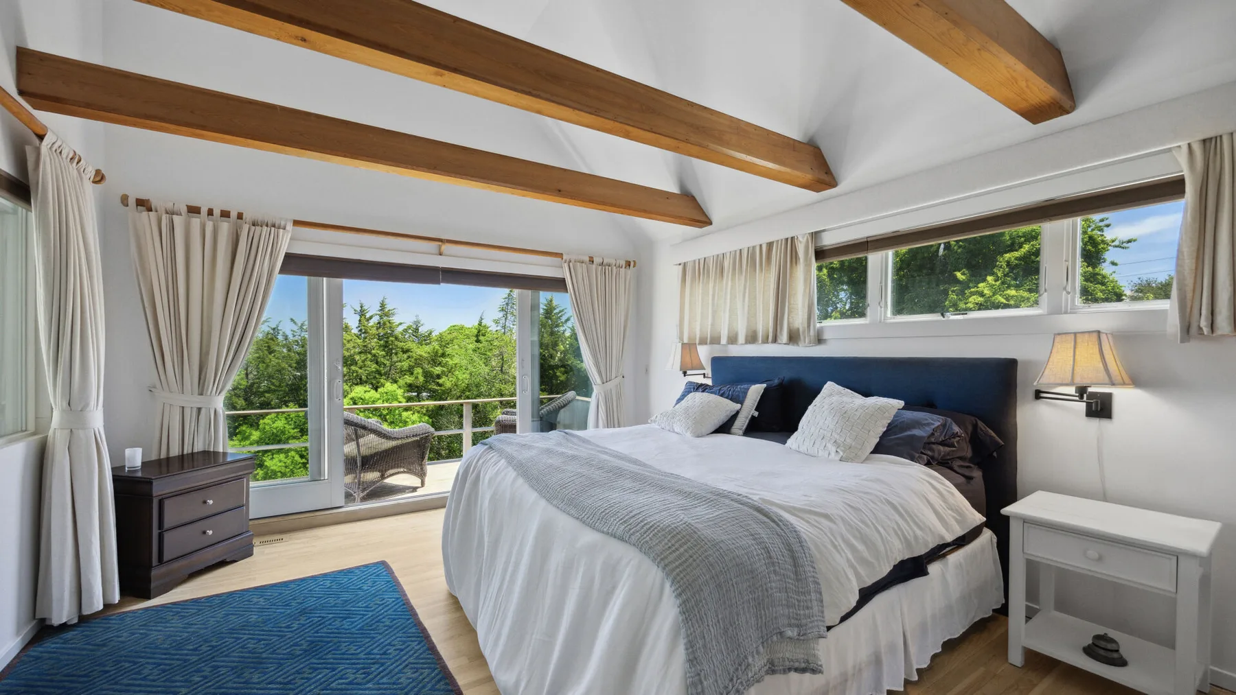A bright bedroom with a large bed and glass doors opening to a balcony.