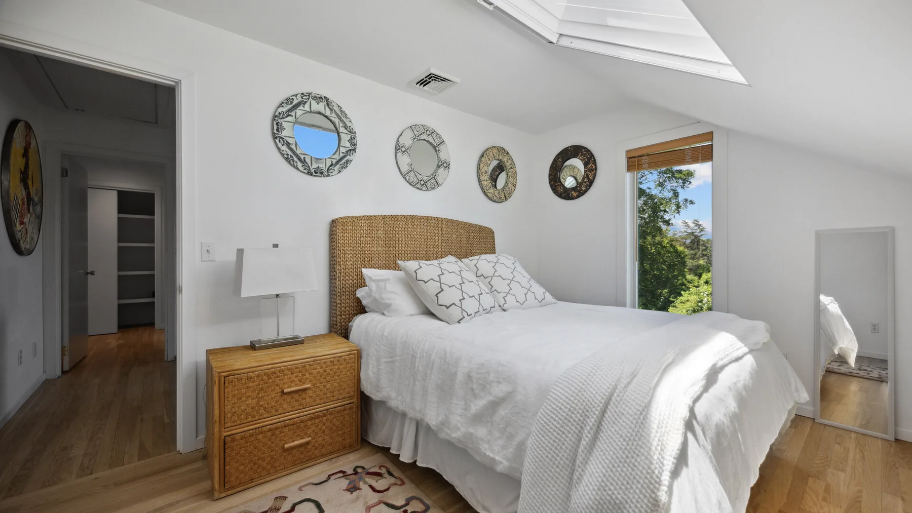 A bright bedroom with a bed, woven headboard, and skylight.