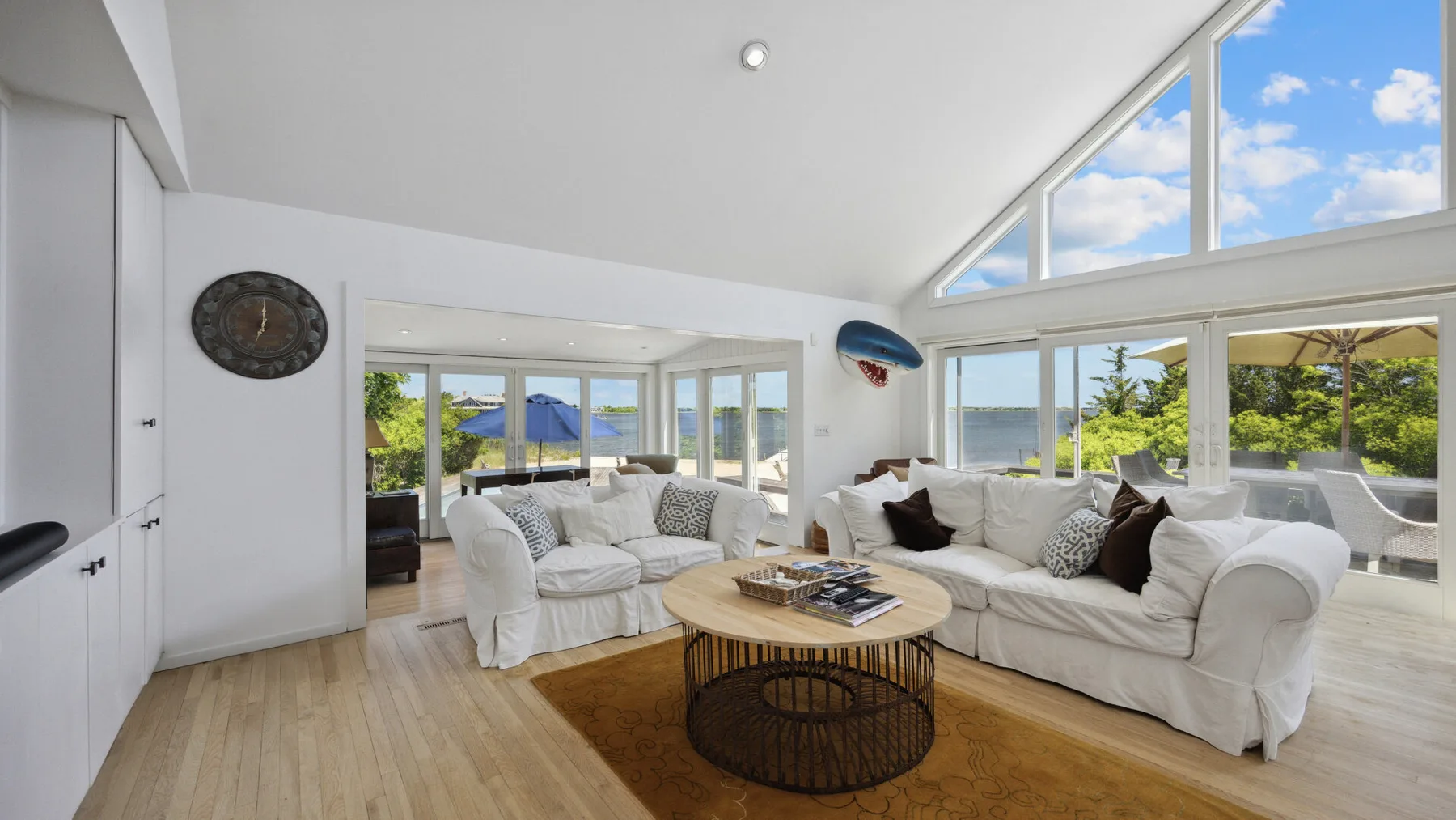 A bright living room with white seating, a round coffee table, and large windows.