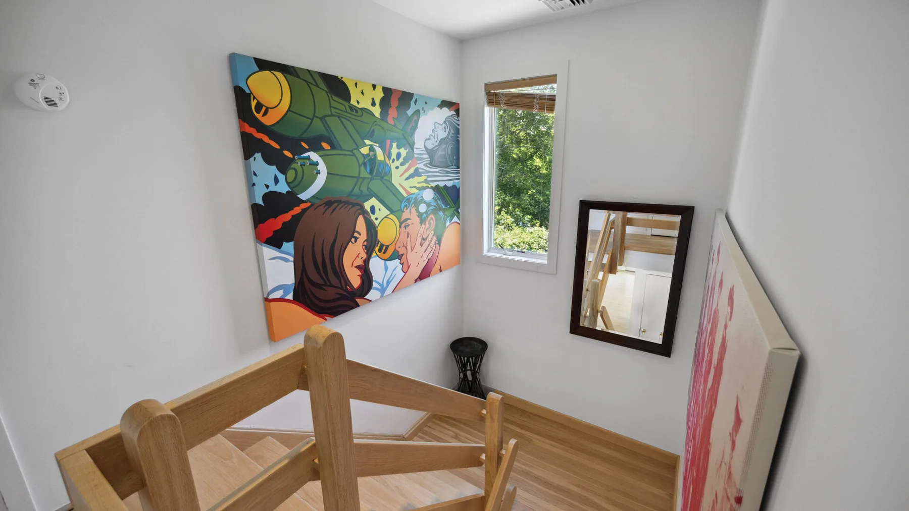 A small room with colorful artwork on the walls and a mirror.