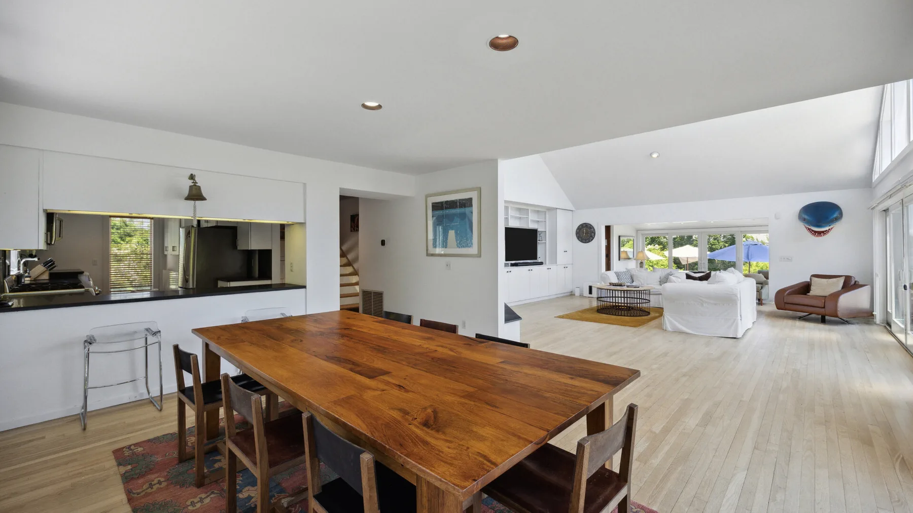 A bright open-plan living and dining area with a large wooden dining table.