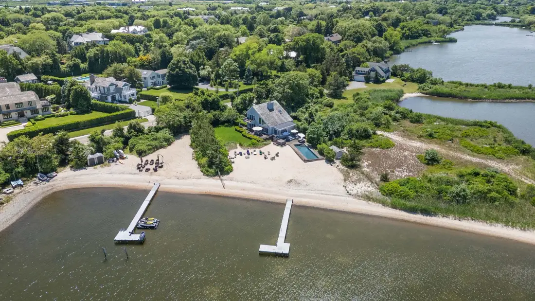 Aerial view of a waterfront property with a sandy beach and two piers.