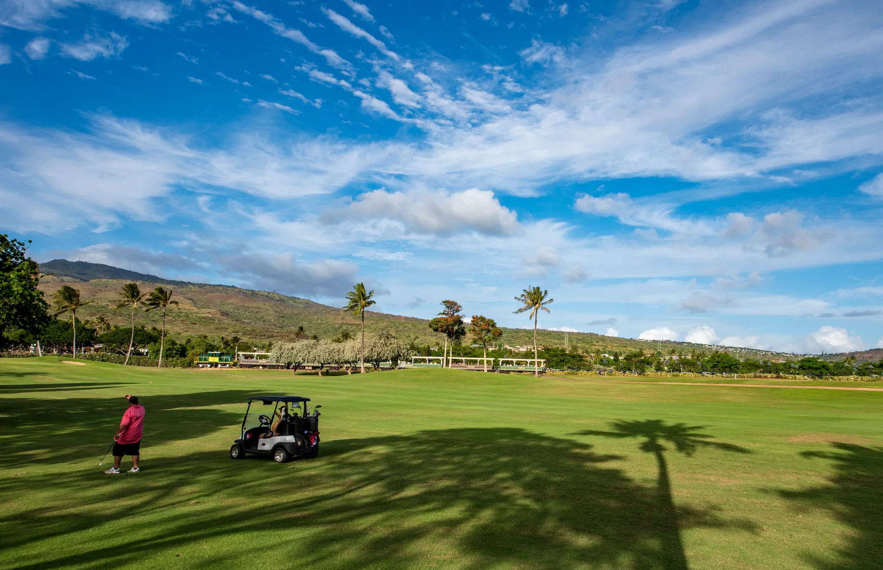Un campo de golf se extiende por un paisaje verde bajo un cielo parcialmente nublado.