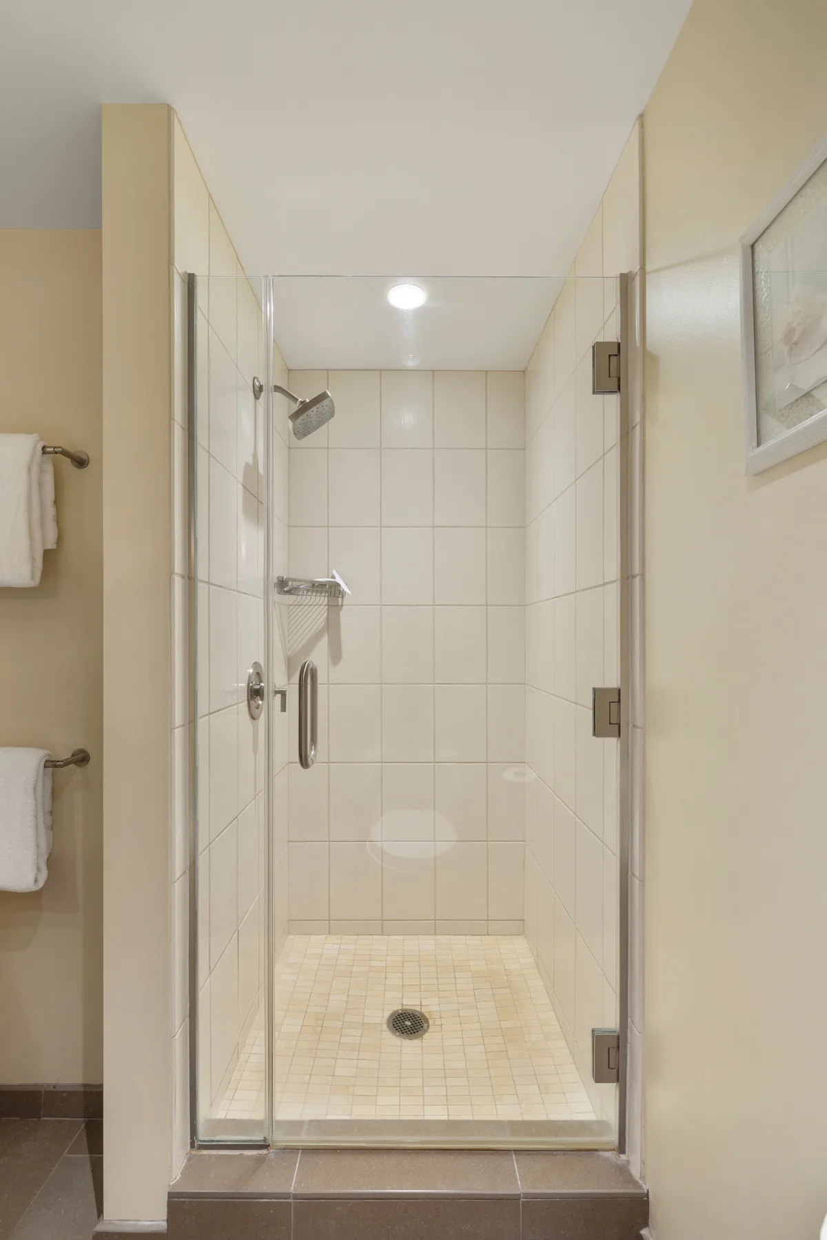 Una zona de ducha con azulejos, paneles de vidrio y una ducha de mano.