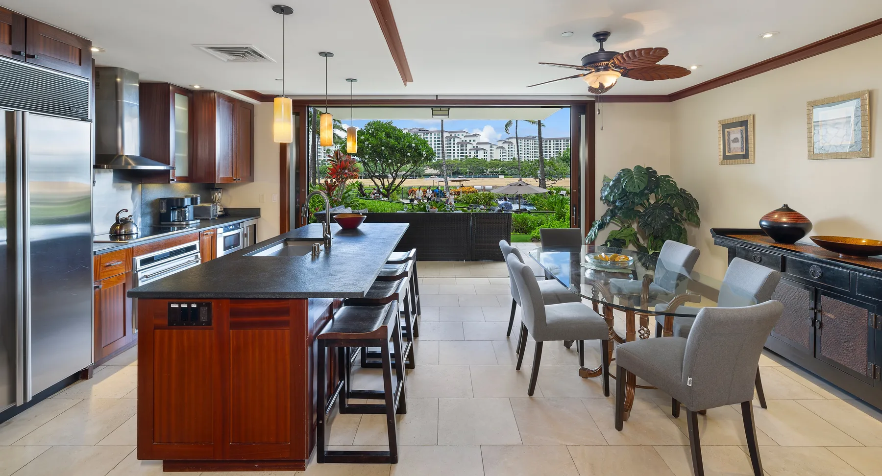 Una cocina y comedor con una isla central y una mesa de comedor de vidrio.