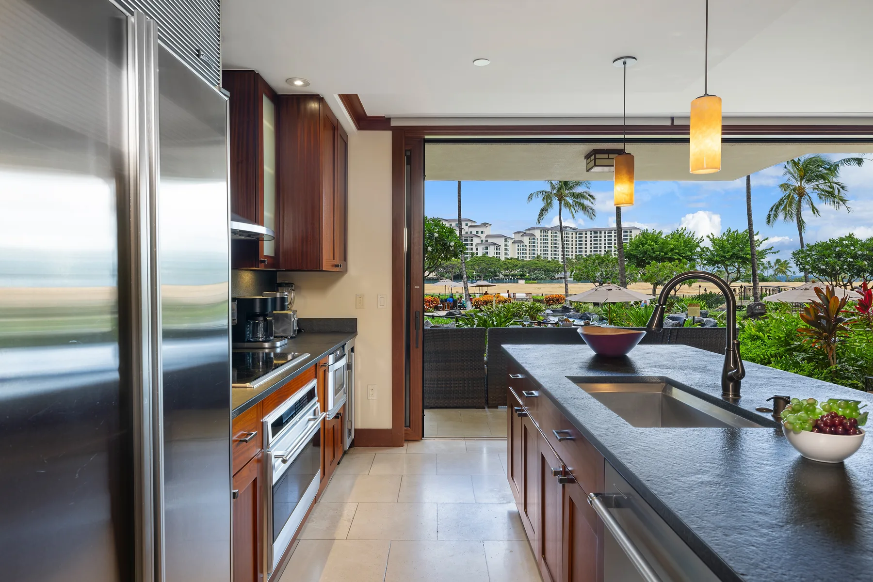 Una cocina moderna se abre a una vista de palmeras y edificios cercanos.