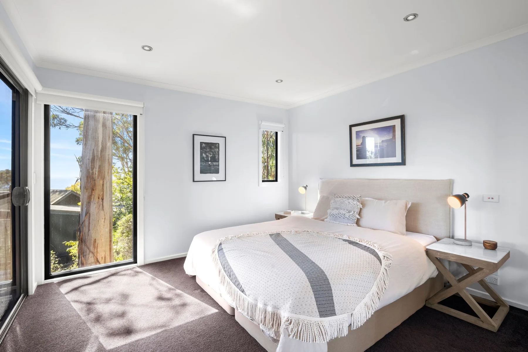 Dormitorio luminoso con una cama bien arreglada y grandes ventanas.