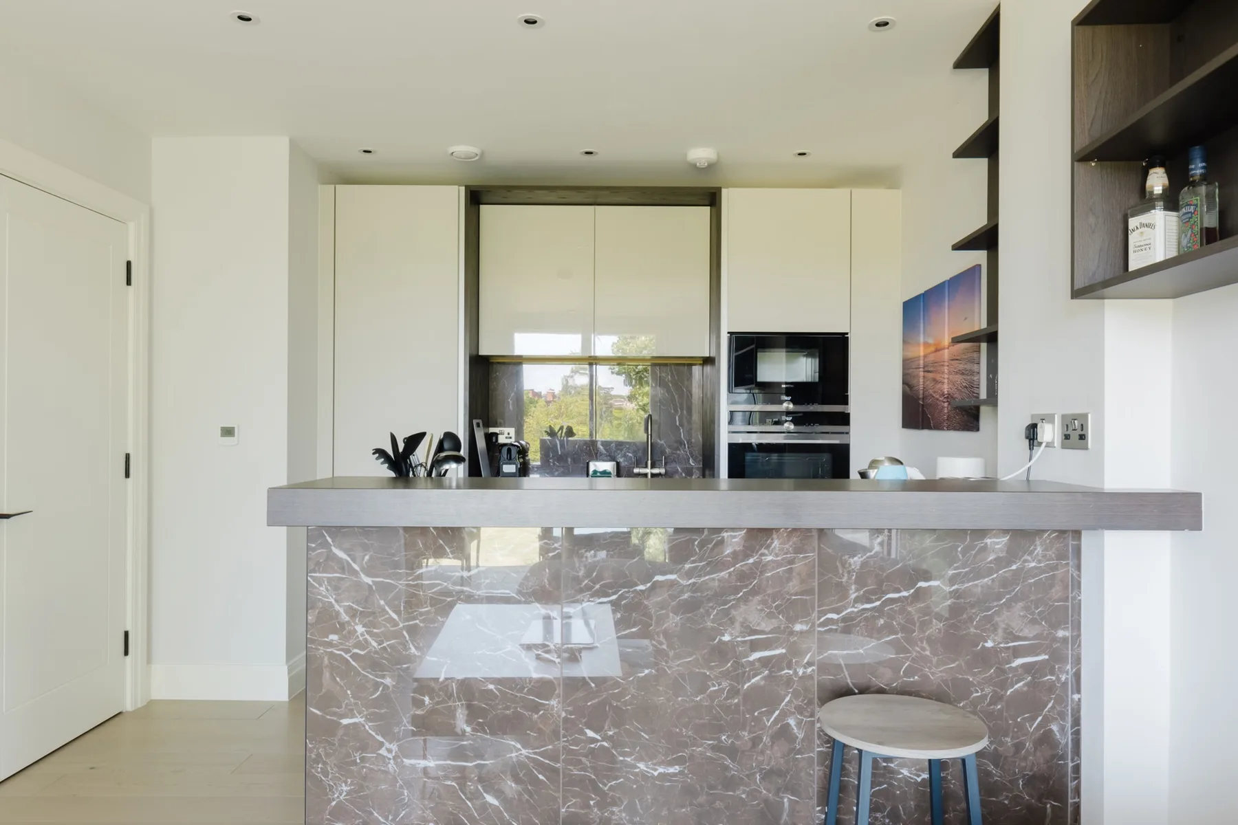 A modern kitchen with a wide stone-fronted island and built-in appliances.