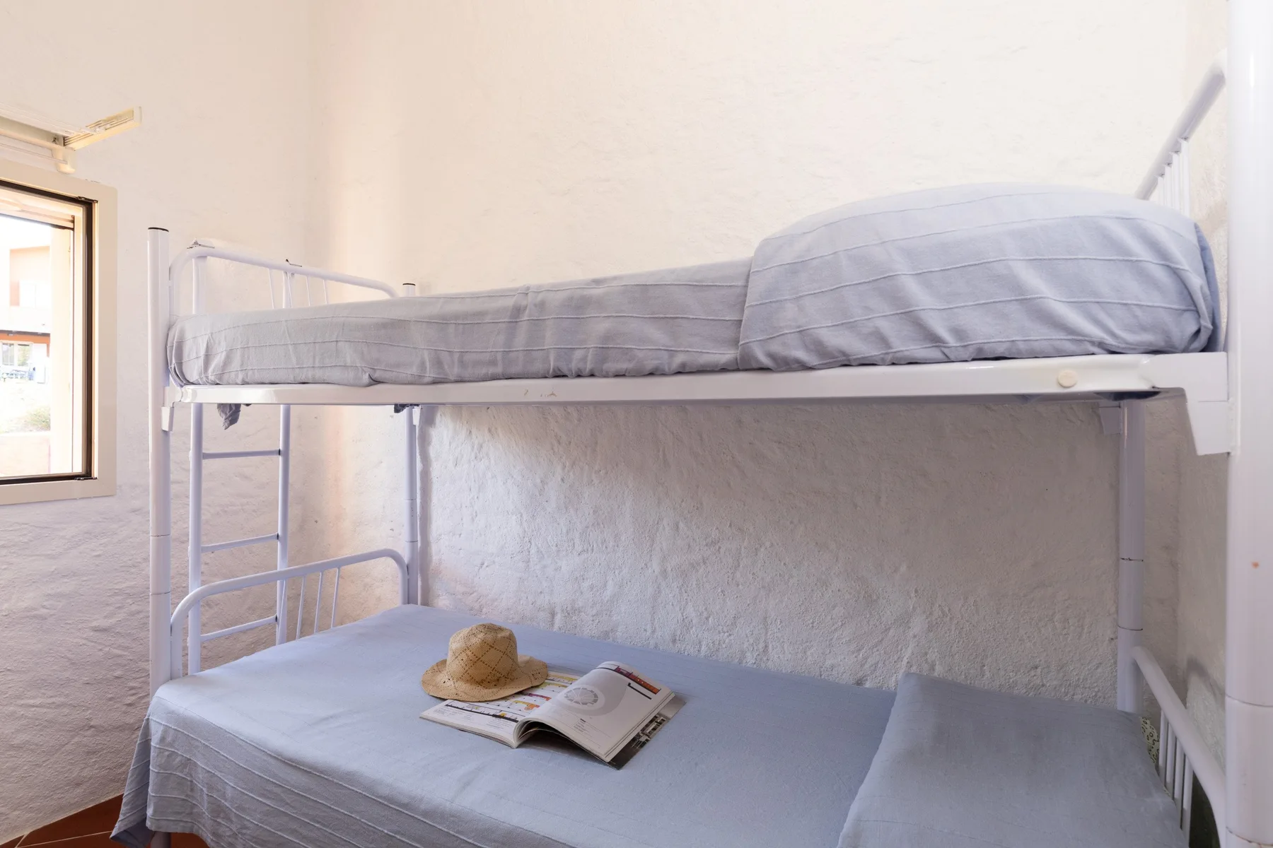 A bunk bed with gray bedding and a book sits in a bright bedroom.
