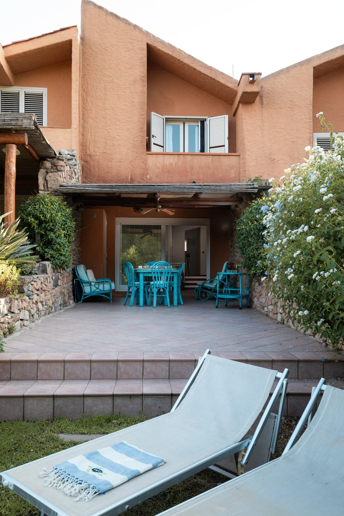 A tiled patio with turquoise seating sits beneath a peach-colored exterior.