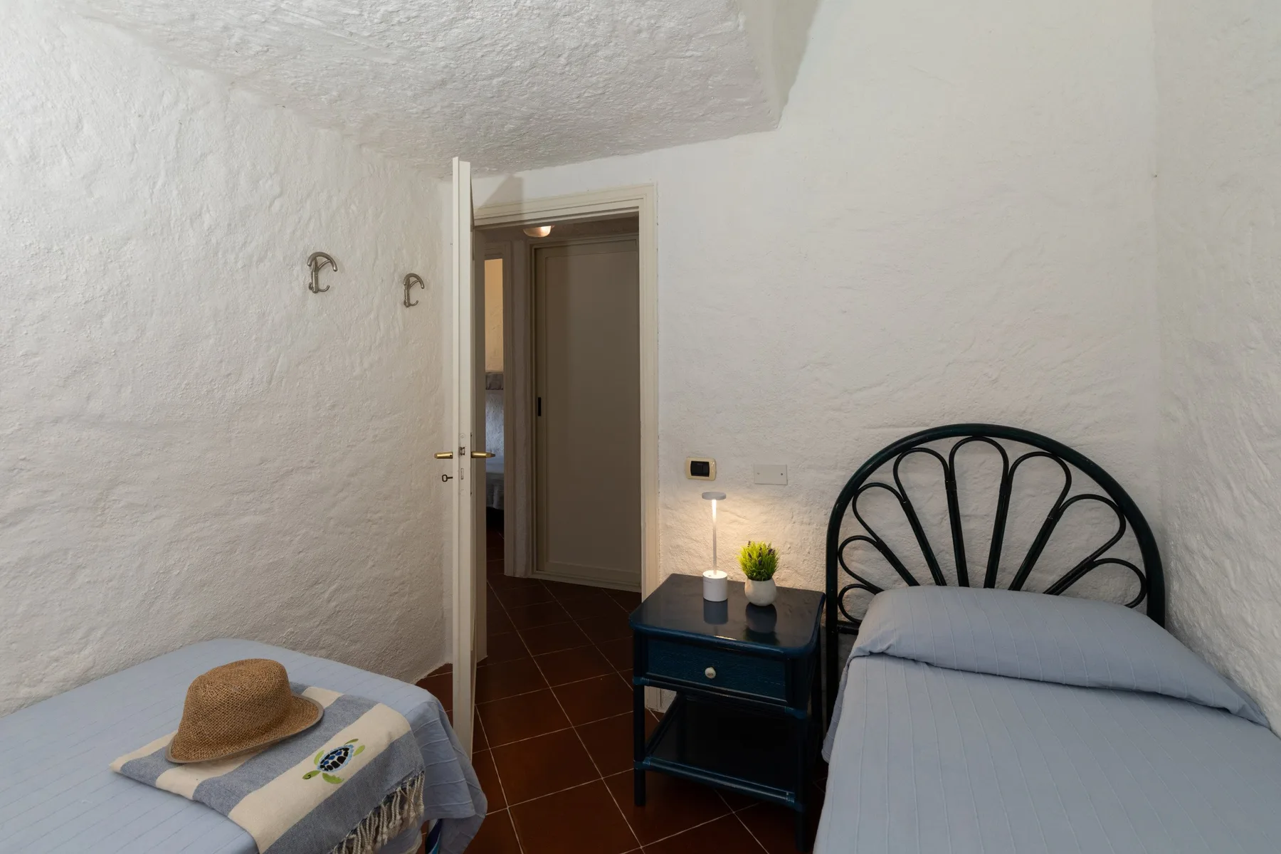 A small bedroom with a single bed, a narrow table, and a doorway.