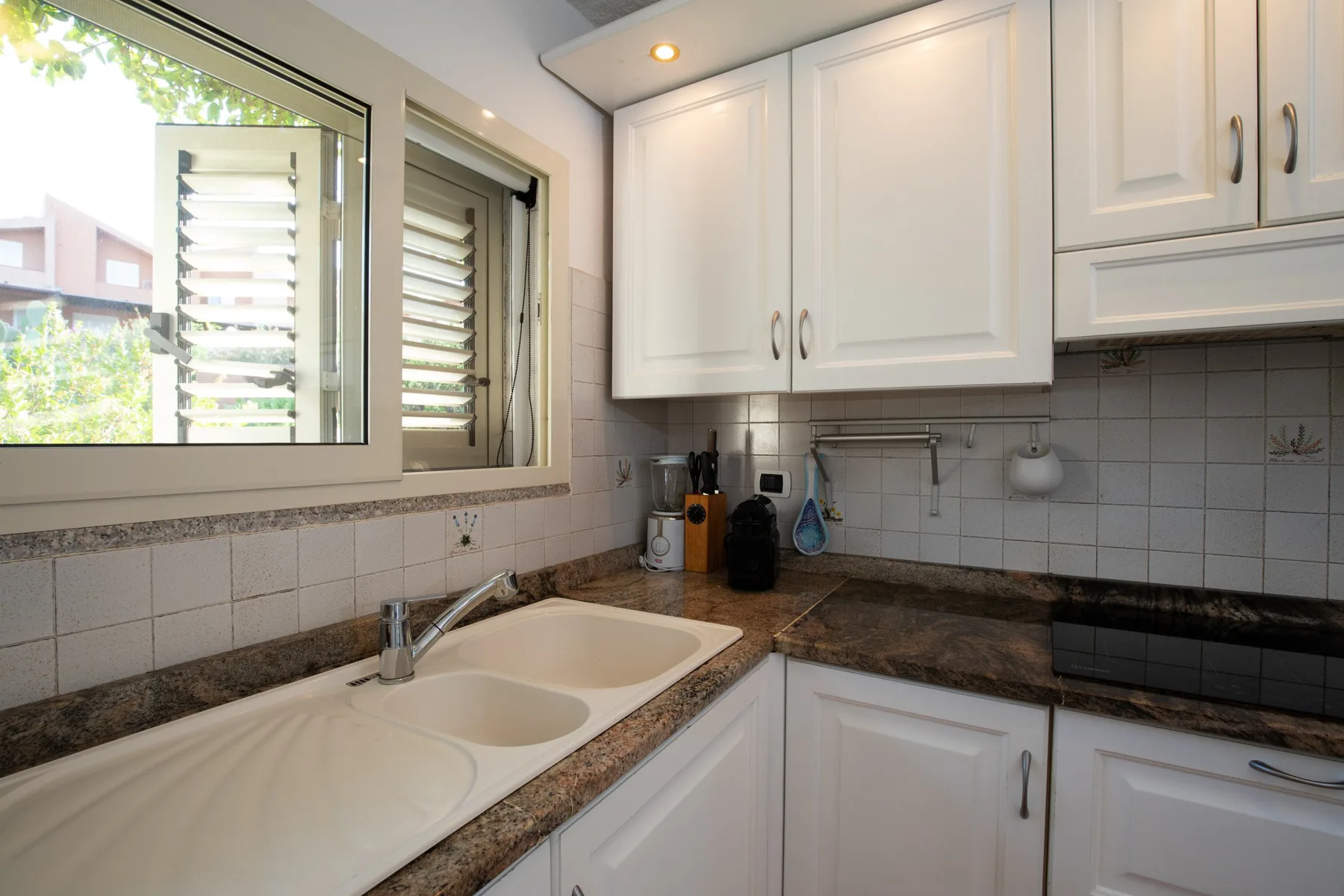 A bright kitchen with a double-basin sink, countertop, and white cabinets.