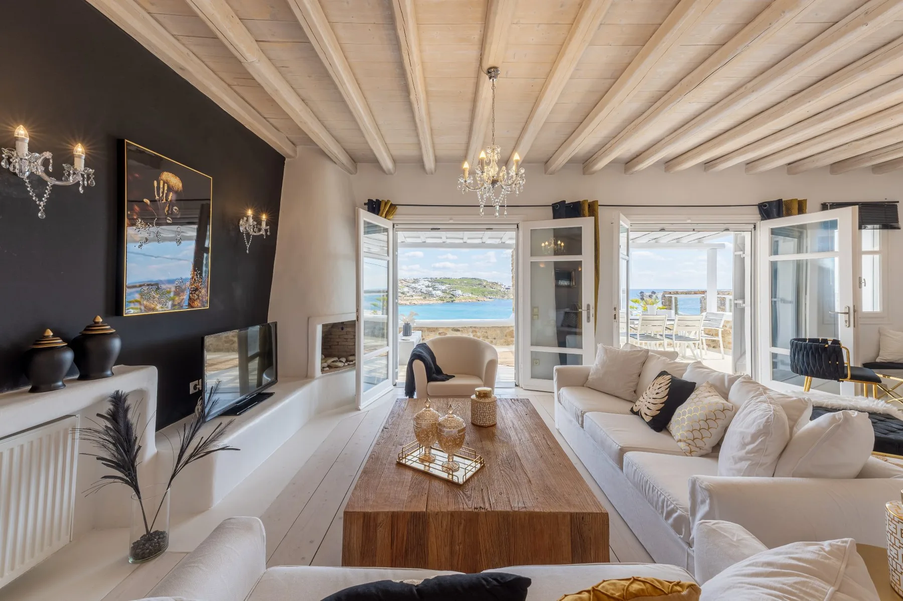 A bright living room opens onto a balcony with a view of the sea.