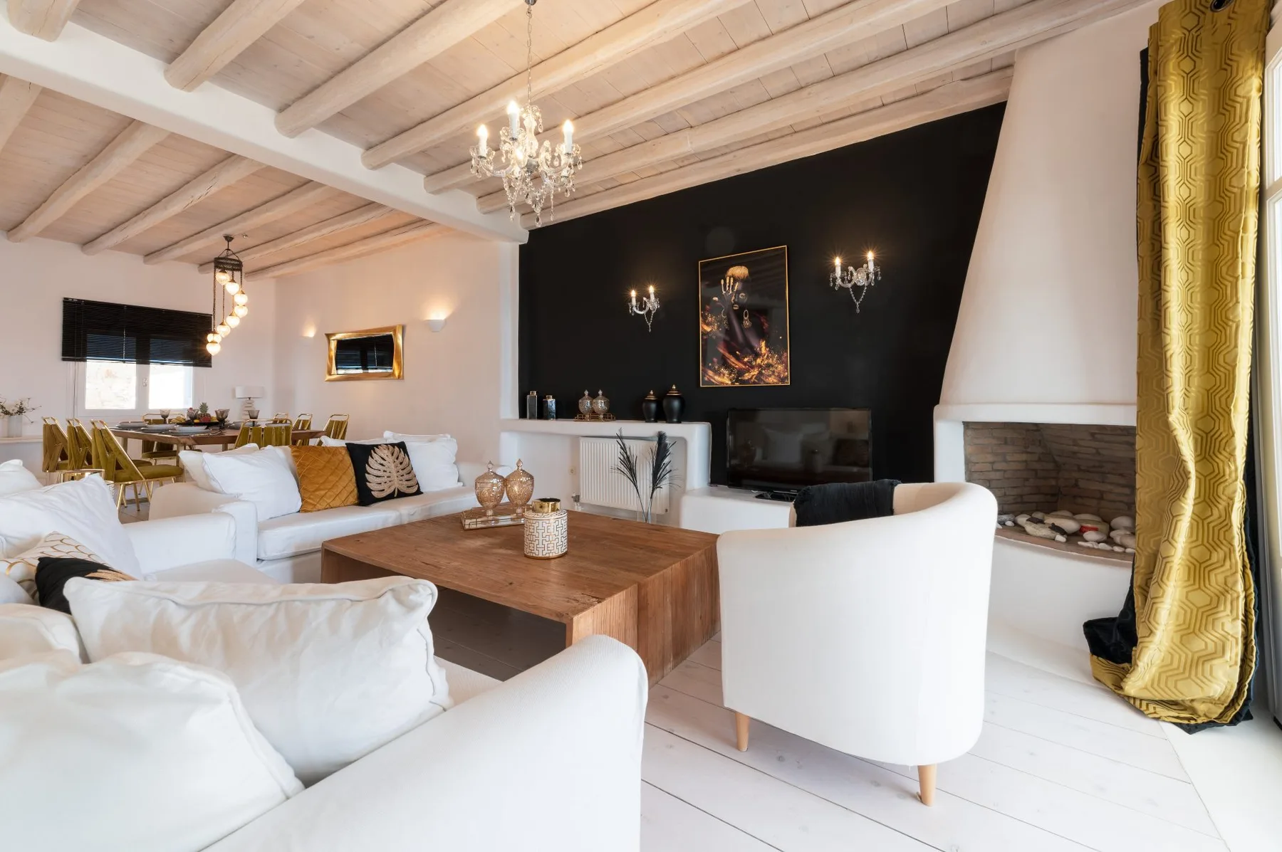 A bright living room with white seating, a wooden coffee table, and a fireplace.