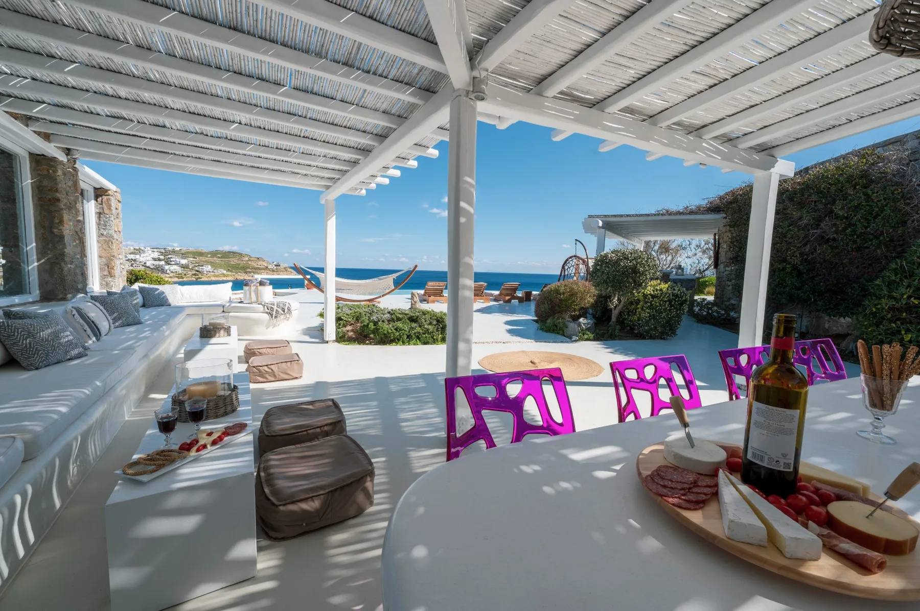 A shaded outdoor dining and lounge area overlooks the sea.