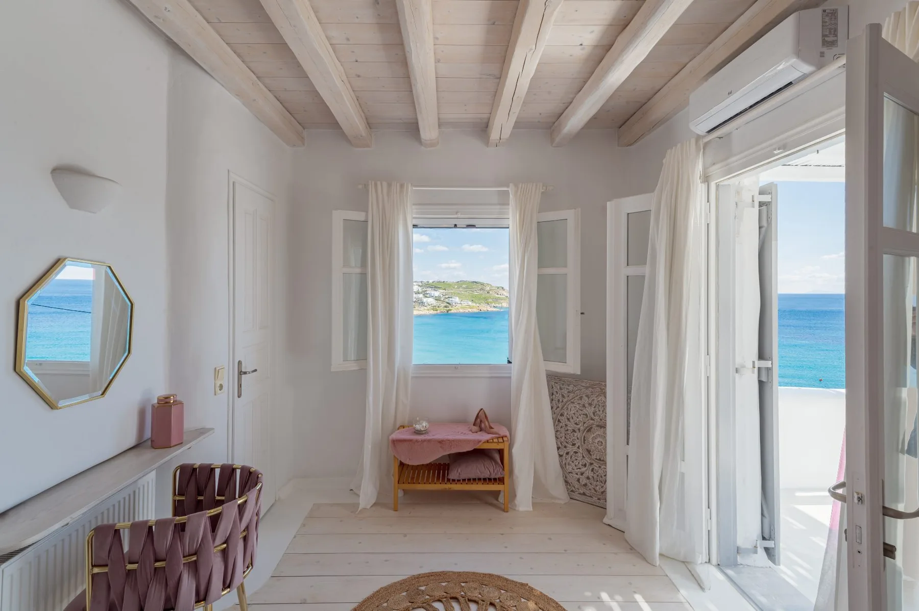 A bright room with open doors overlooking the sea.