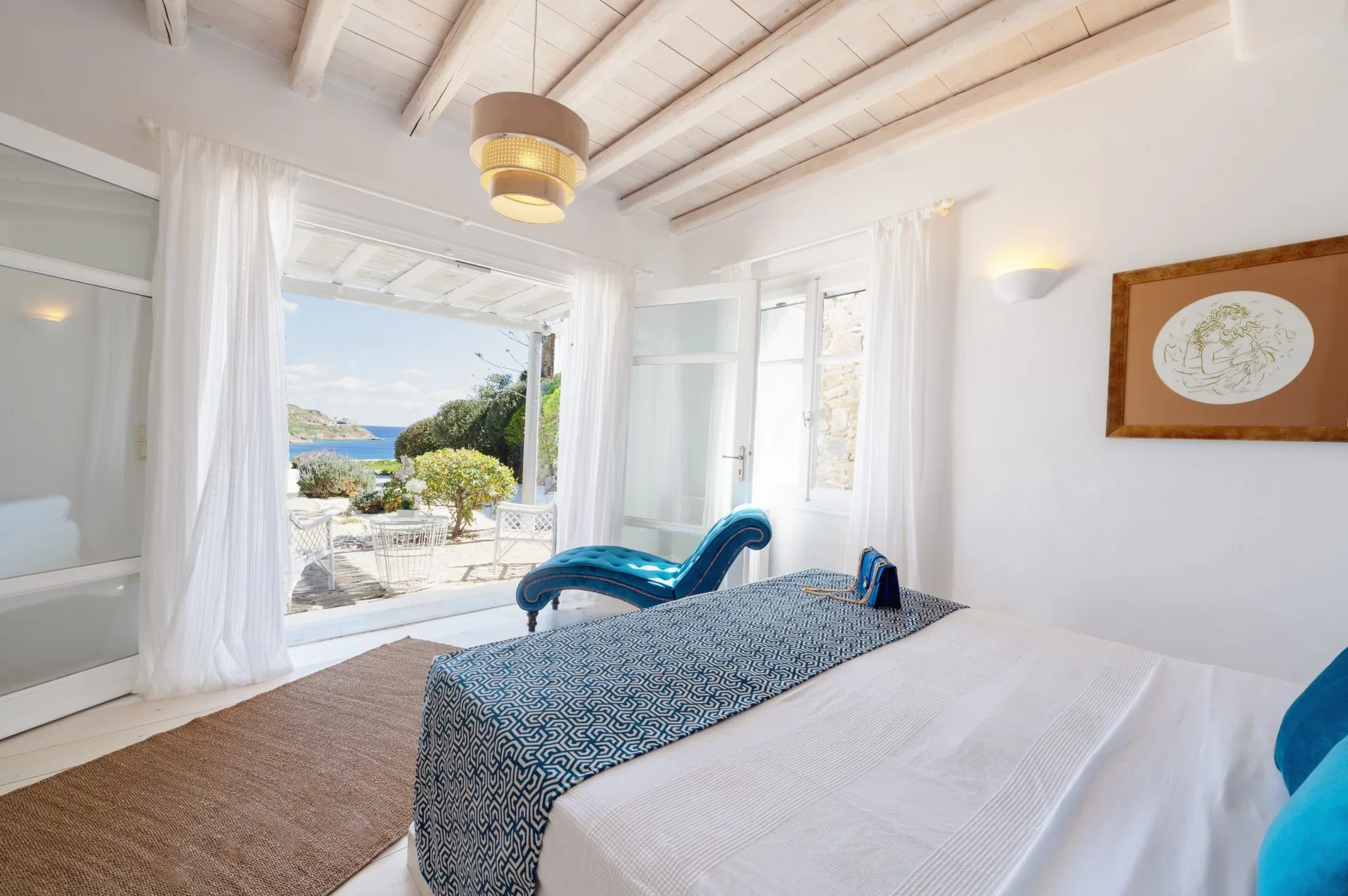 A bright bedroom opens onto a terrace with a view of the sea.