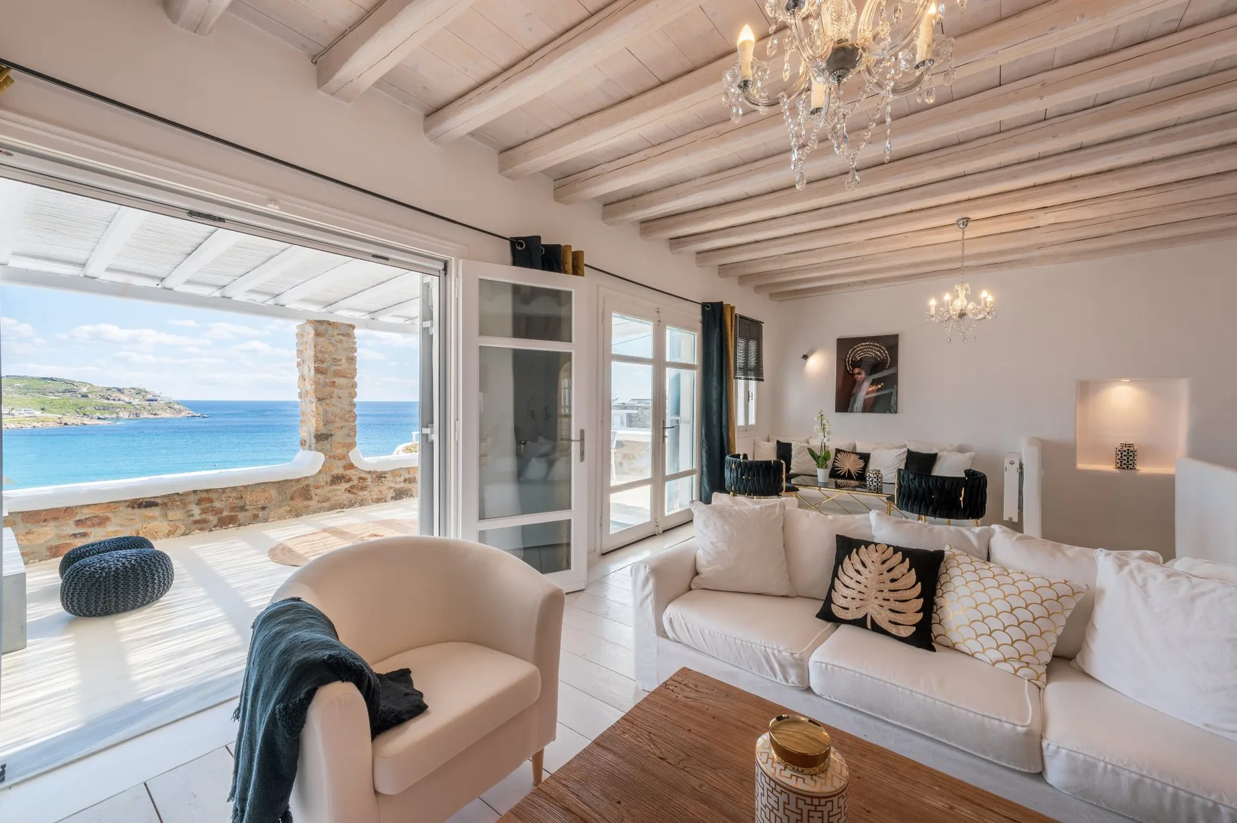 A bright living room with pale seating and a wide view of the sea.