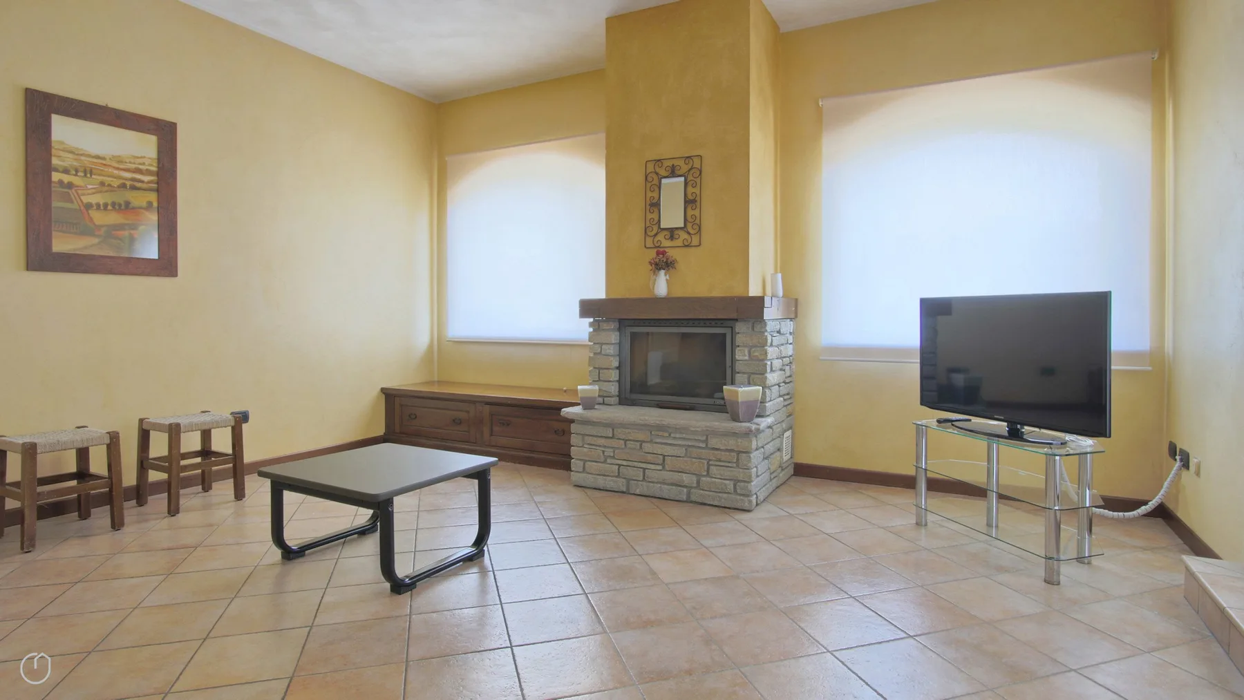 Una sala de estar con chimenea de piedra, asientos y un televisor.
