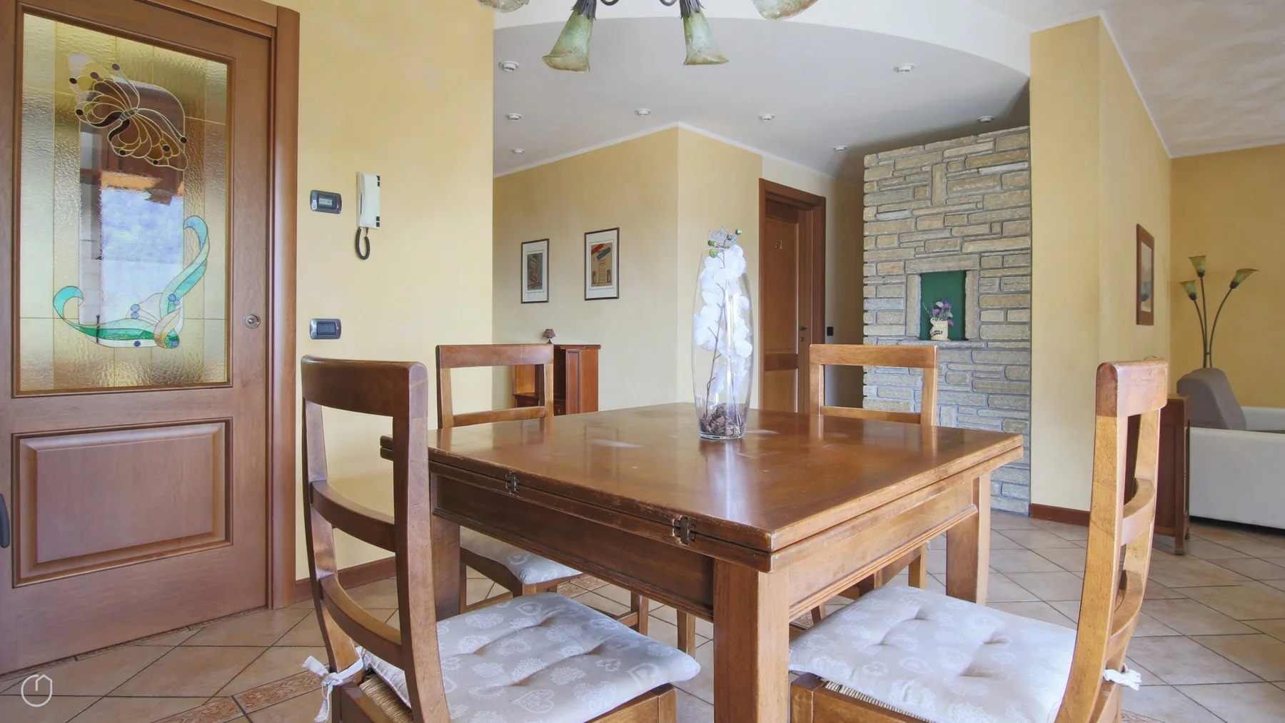 Dining area with a wooden table and chairs beside a stone fireplace.