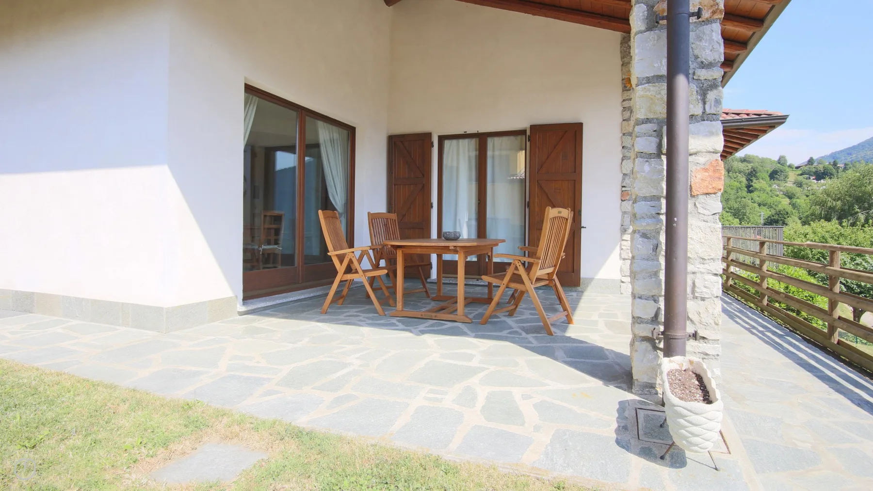 A covered outdoor patio with a wooden table and chairs.