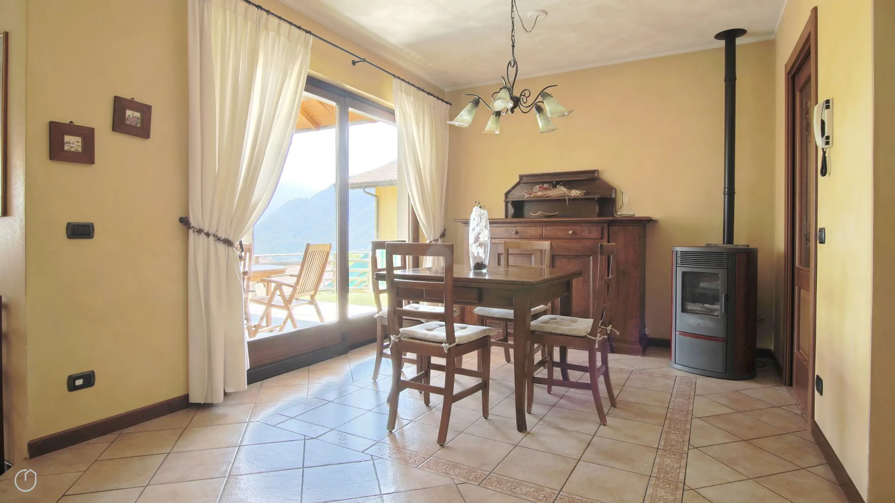 A dining area with a wooden table and chairs beside a glass door.