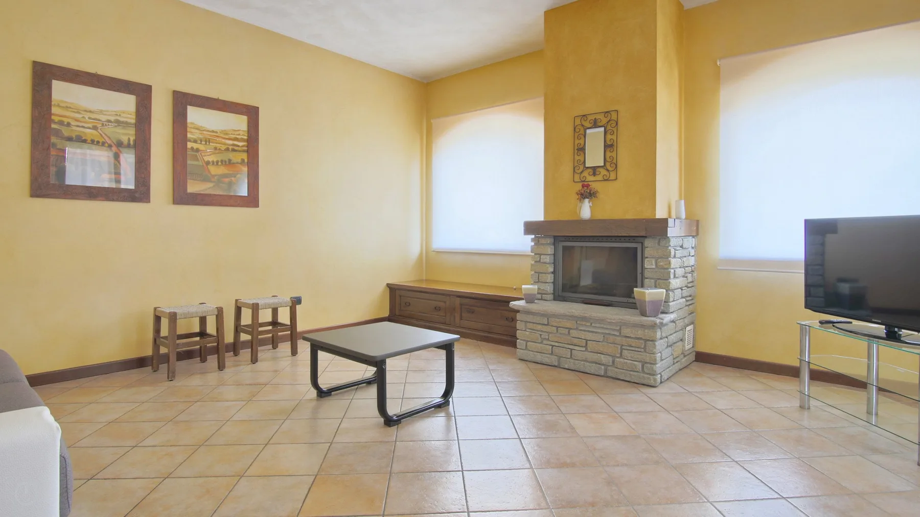 A living room with a stone fireplace, seating, and a television.