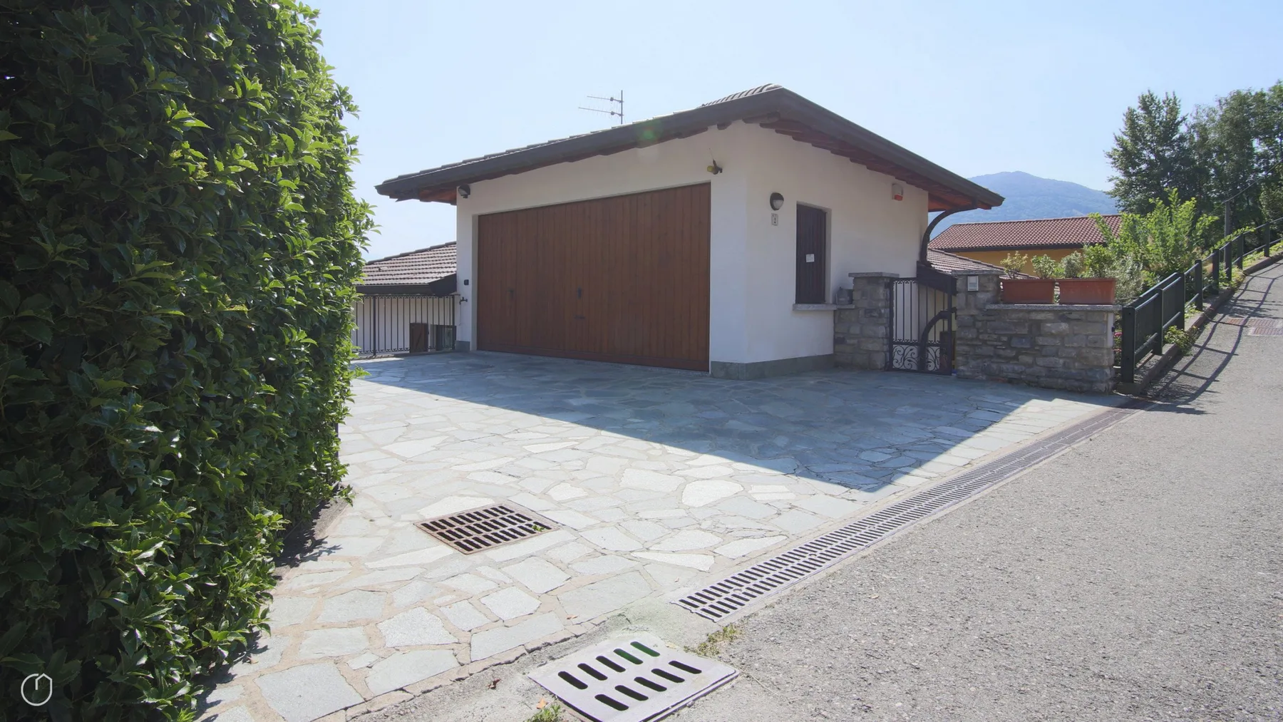 A paved driveway leads to a small white building with a large wooden garage door.