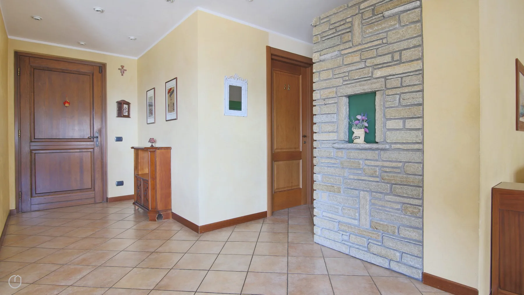 An interior entryway with tiled flooring, wooden doors, and a stone feature wall.