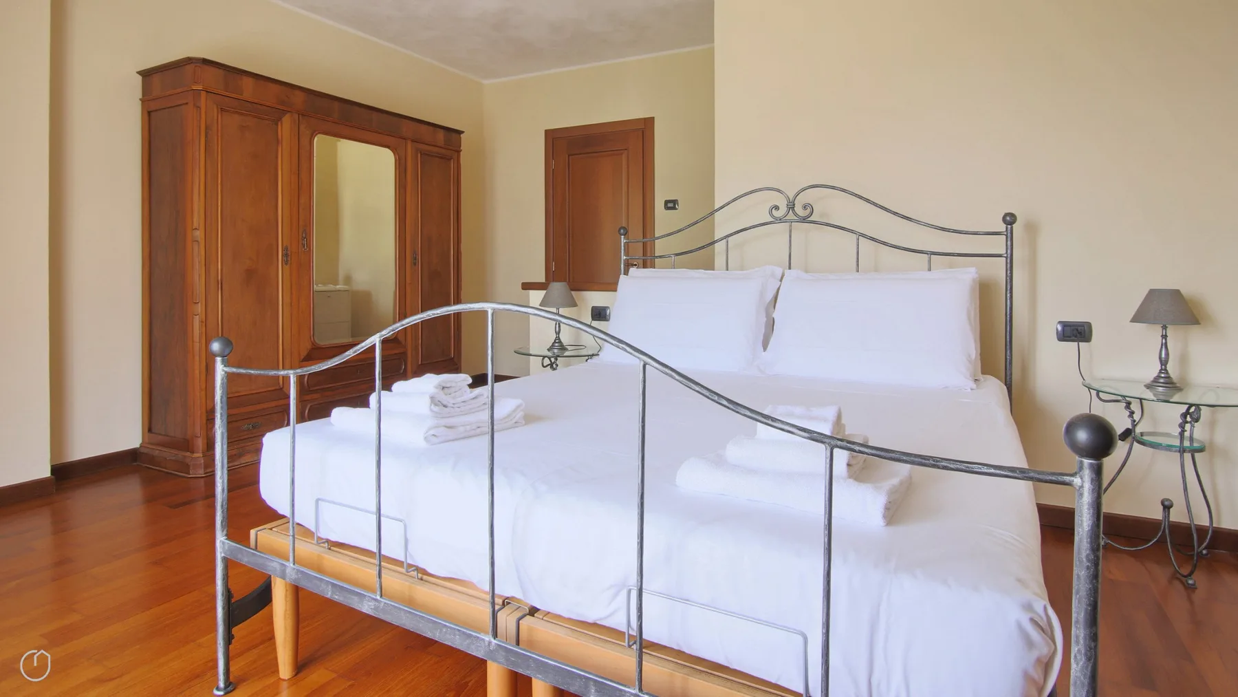 A bedroom with a neatly made bed and a wooden wardrobe.