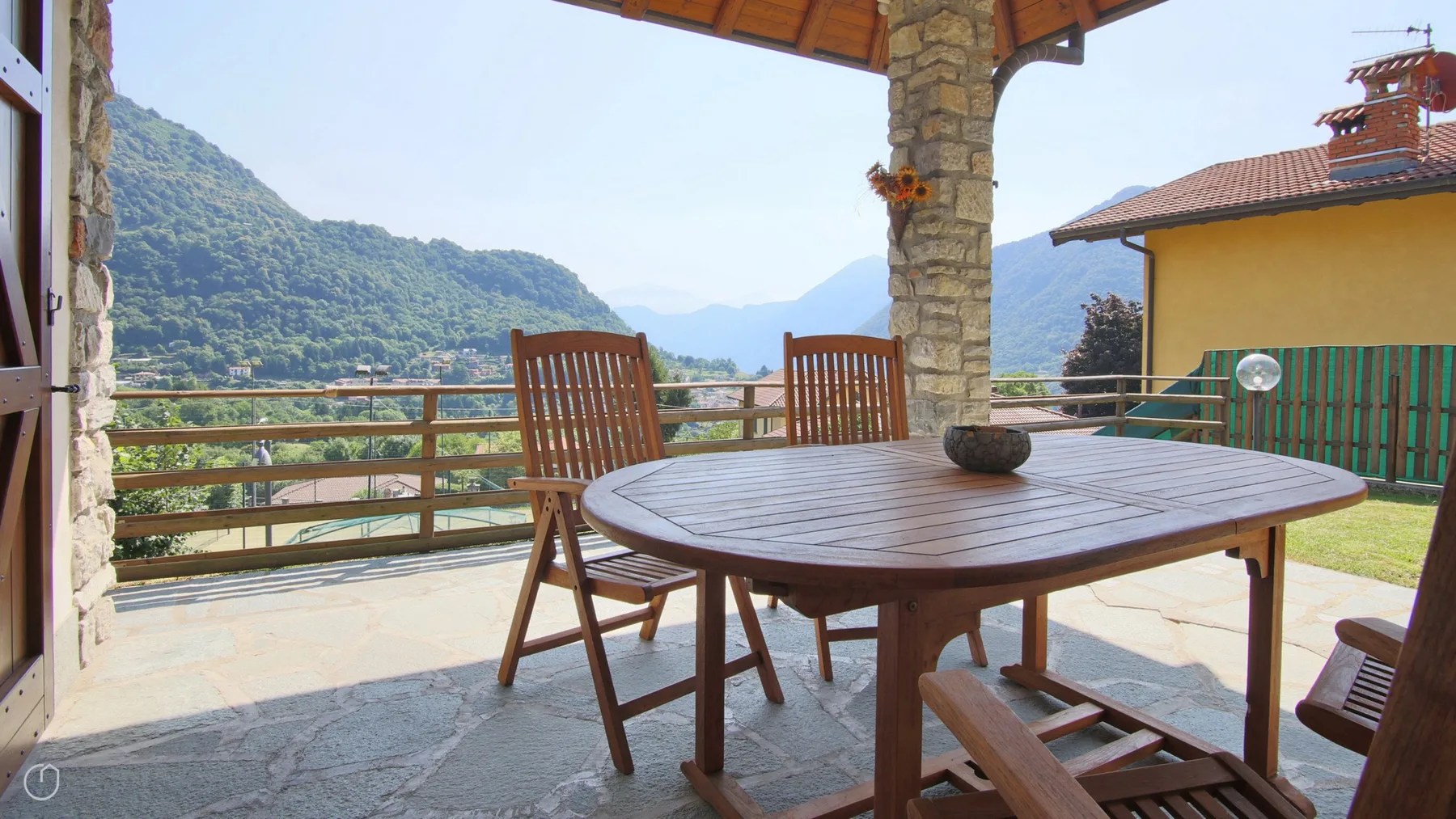 A covered outdoor dining area overlooks green mountains.