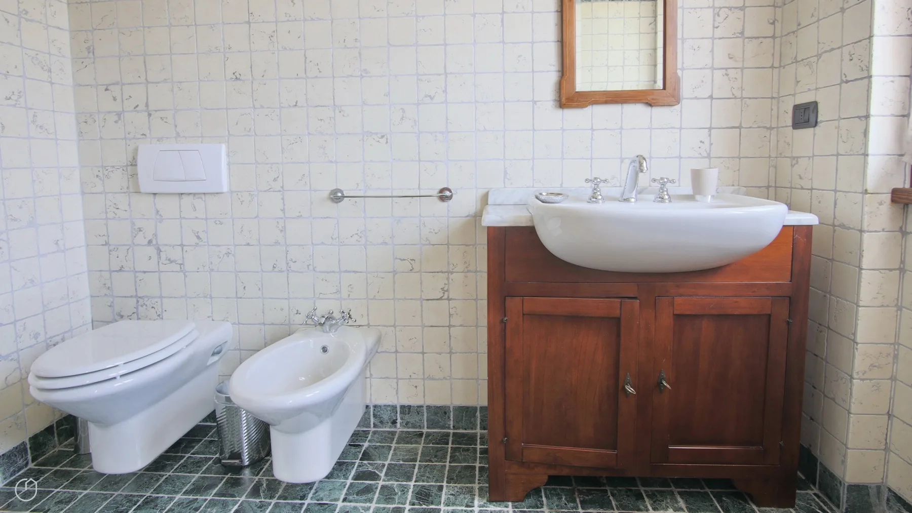 A tiled bathroom with a sink, toilet, and wooden vanity.