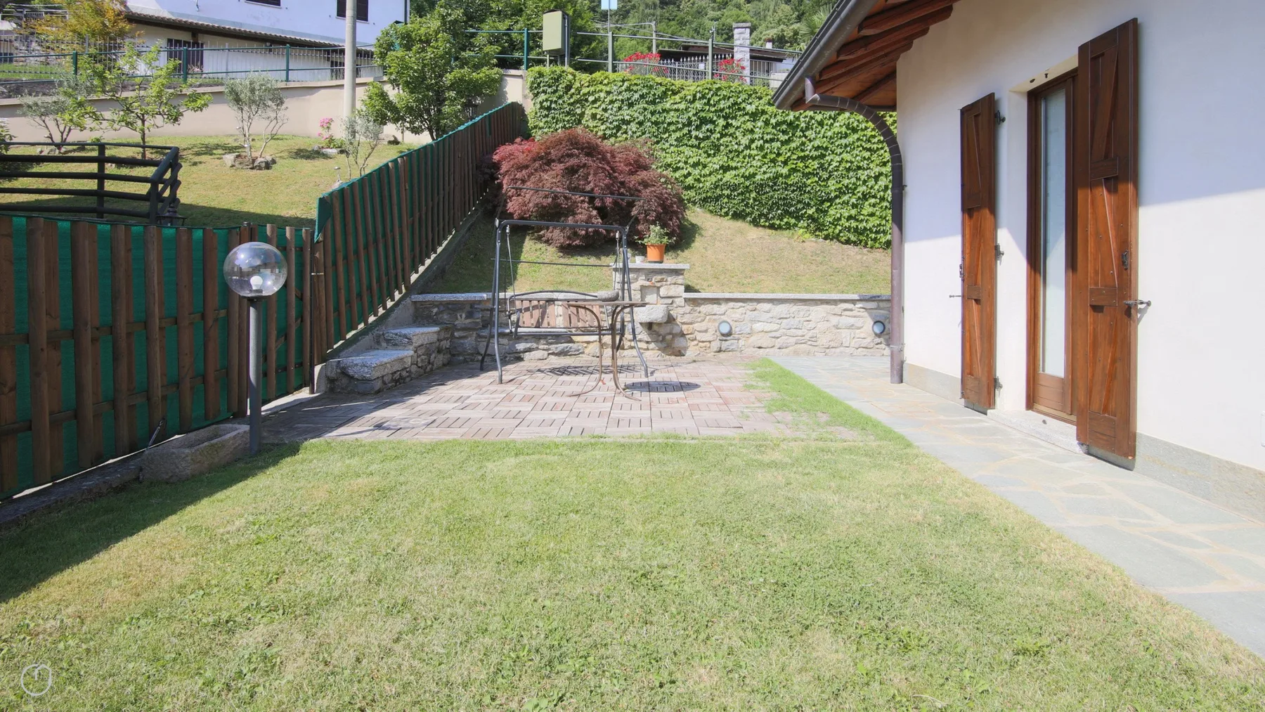 A grassy yard beside a paved patio and a light-colored building.