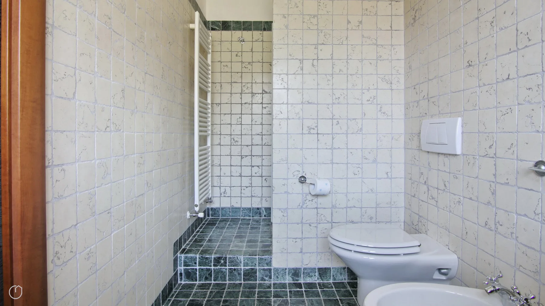 A tiled bathroom with a toilet and shower area.